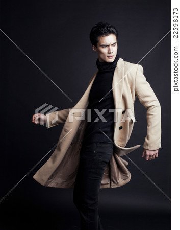 cool real young man in coat on black background 22598173