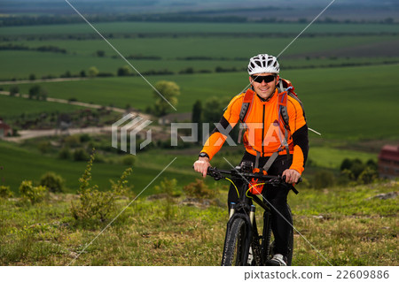 Young man cycling on a rural road through green Young man cycling on a rural road through green 22609886