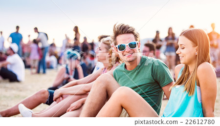 Teenagers at summer music festival, sitting on the 22612780