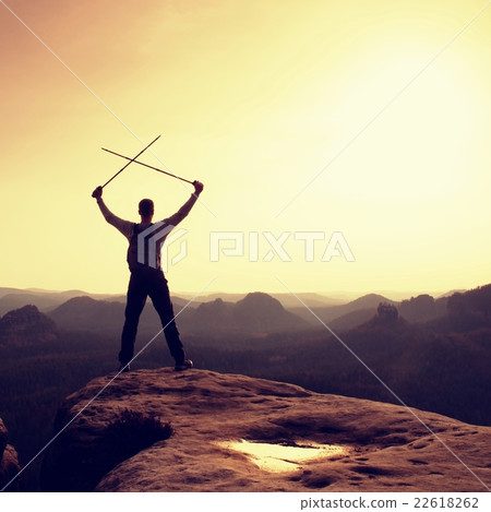 Man with crossed poles above head on cliff. Man with crossed poles above head on cliff. 22618262