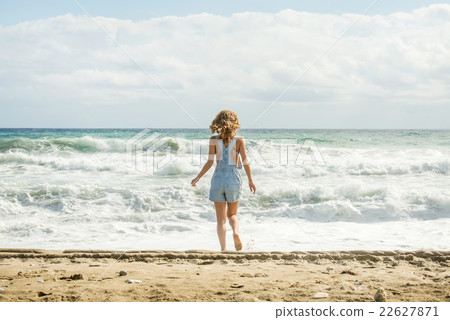 Young woman in blue denim jumpsuit walking to the 22627871