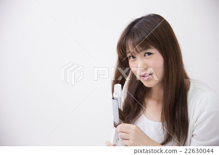 Woman using hair iron · white back 22630044
