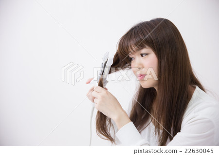 使用頭髮鐵的婦女·白色後面 使用頭髮鐵的婦女·白色後面 22630045