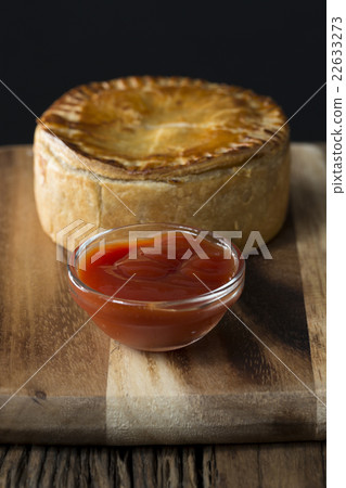 A Traditional British meat pie sitting on a rustic wooden table. A Traditional British meat pie sitting on a rustic wooden table. 22633273