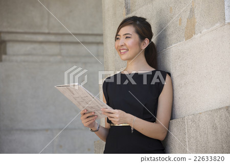Chinese business woman reading a newspaper outside an office bui Chinese business woman reading a newspaper outside an office bui 22633820