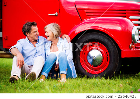 Senior couple sitting at the red vintage car 22640425