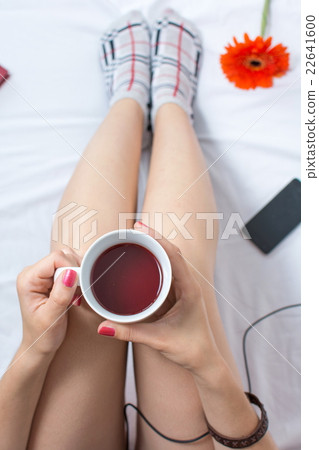 Woman with cup of tea in bed Woman with cup of tea in bed 22641600