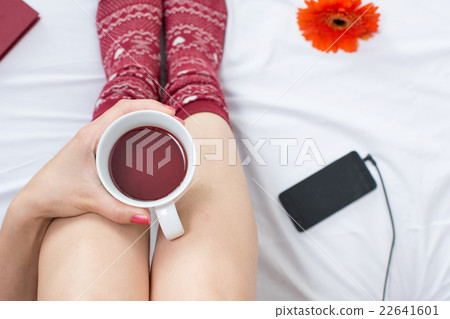 Woman with cup of tea in bed 22641601