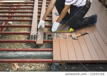 Worker installing wood floor for patio 22645168