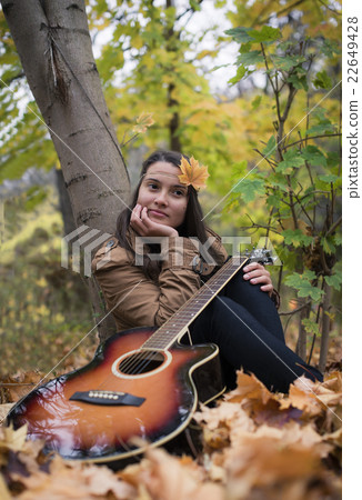 Meditative girl with a guitar in autumn Meditative girl with a guitar in autumn 22649428