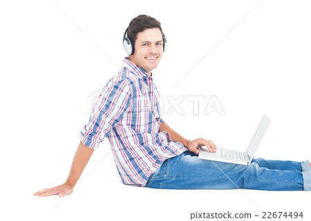 Man with headphones sitting on the floor using laptop Man with headphones sitting on the floor using laptop 22674494