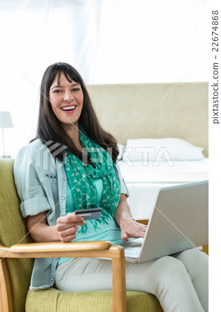 Happy pregnant woman shopping online on her laptop Happy pregnant woman shopping online on her laptop 22674868