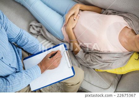 Doctor writing on clipboard while consulting pregnant woman 22675367