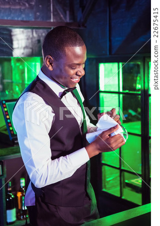 Smiling bartender cleaning a glass Smiling bartender cleaning a glass 22675415