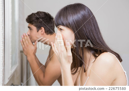 Young couple looking at face in mirror 22675580