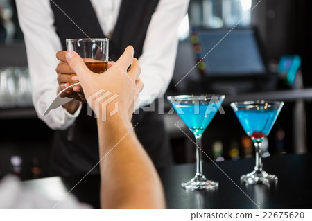 Bartender serving whiskey at bar counter Bartender serving whiskey at bar counter 22675620