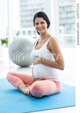 Pregnant woman touching her stomach while exercising Pregnant woman touching her stomach while exercising 22675724