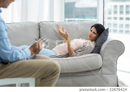 Doctor writing on notepad while consulting pregnant woman Doctor writing on notepad while consulting pregnant woman 22676424