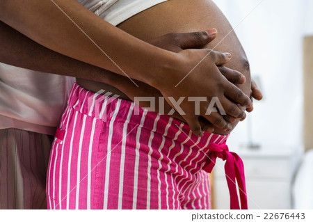 Pregnant couple embracing in bedroom Pregnant couple embracing in bedroom 22676443