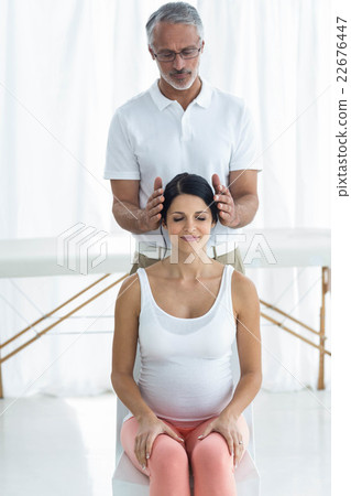 Pregnant woman receiving a head massage from masseur Pregnant woman receiving a head massage from masseur 22676447