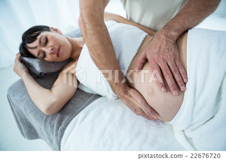 Pregnant woman receiving a stomach massage from masseur Pregnant woman receiving a stomach massage from masseur 22676720