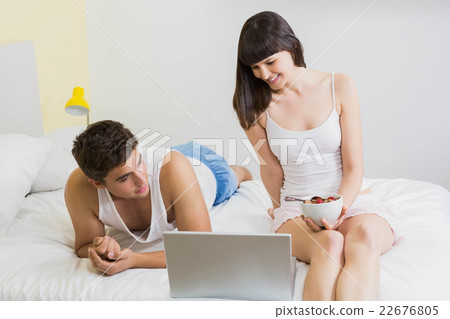 Young couple looking at laptop on bed Young couple looking at laptop on bed 22676805