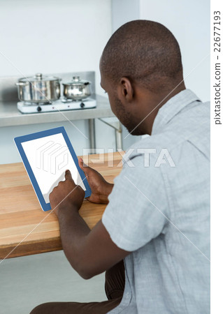 Man using digital tablet in kitchen Man using digital tablet in kitchen 22677193