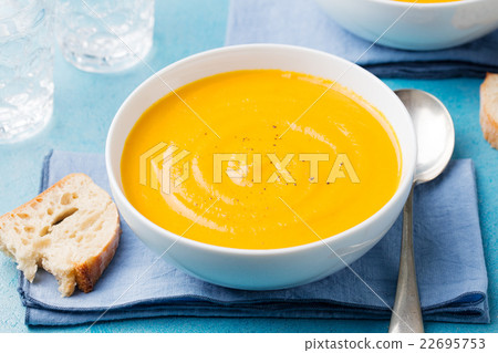 Pumpkin and carrot soup on blue stone background. Pumpkin and carrot soup on blue stone background. 22695753