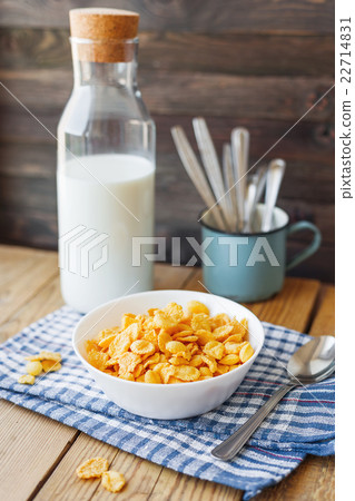 Tasty corn flakes in white bowl with milk bottle 22714831