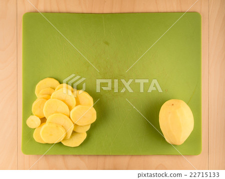Whole and sliced potatoe on green plastic board 22715133