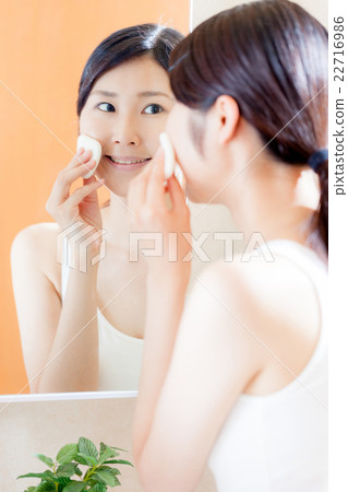 Woman putting foundation, puff, mirror 22716986