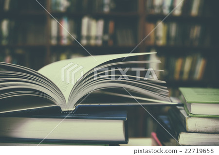 Close up of open book and Stack of books on desk Close up of open book and Stack of books on desk 22719658