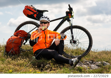 Active man sitting near the bike and eating 22723029