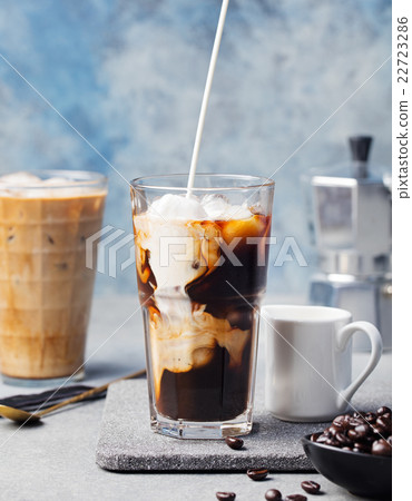 Ice coffee in a tall glass with cream poured over 22723286