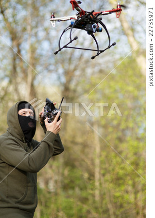 Man in mask operating a drone with remote control. Man in mask operating a drone with remote control. 22735971