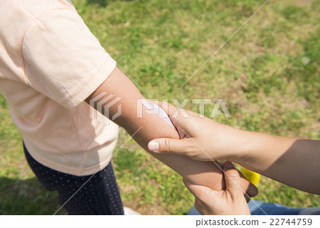 Apply sunscreen to children's arms 22744759