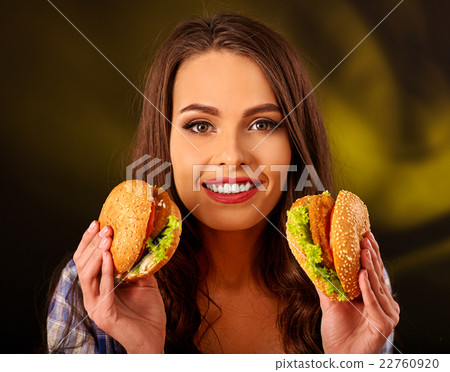 Happy girl holding two small fastfood hamburgers. 22760920