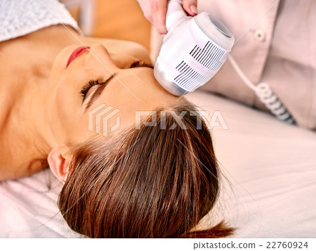 Young woman receiving electric facial massage. 22760924