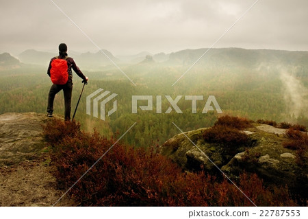Man hiker with trekking poles and red backpack Man hiker with trekking poles and red backpack 22787553