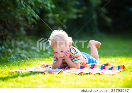 Little boy reading in summer garden Little boy reading in summer garden 22798987