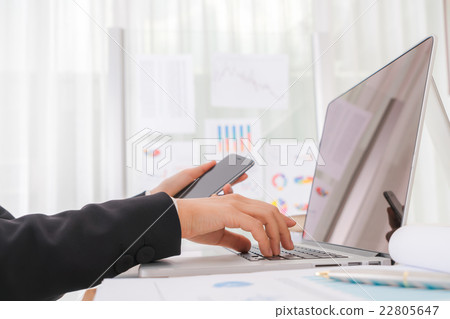 Closeup of business woman hand typing on laptop keyboard with mobile phone Closeup of business woman hand typing on laptop keyboard with mobile phone 22805647