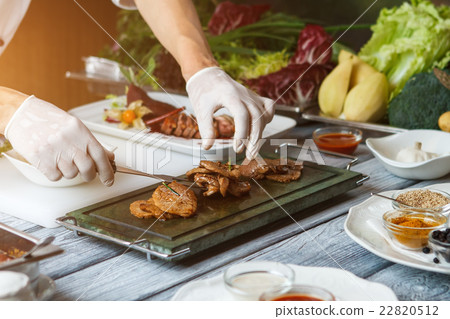 Hand with fork touching meat. 22820512