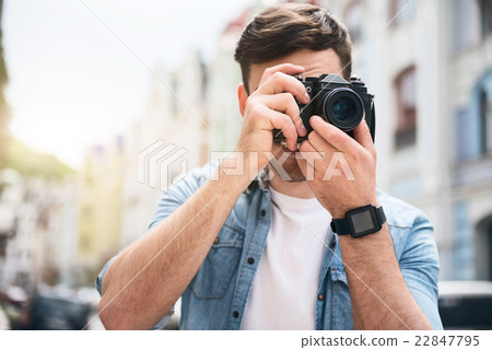 Pleasant cheerful man holding photo camera 22847795