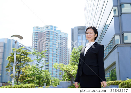 從站立在商業區的一個年輕辦公室工作者的一名婦女 從站立在商業區的一個年輕辦公室工作者的一名婦女 22848357