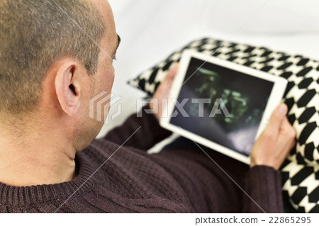 man watching a movie or a series in his tablet man watching a movie or a series in his tablet 22865295