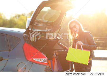 Woman putting her shopping bags into the car trunk 22885991