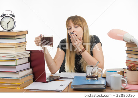 Girl student doing night yawns, holding another cup of coffee hands Girl student doing night yawns, holding another cup of coffee hands 22886350