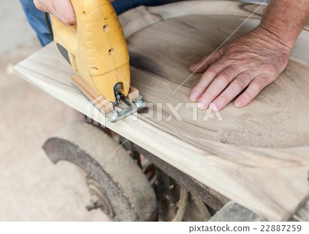 Carpenter is cutting a board with fretsaw 22887259
