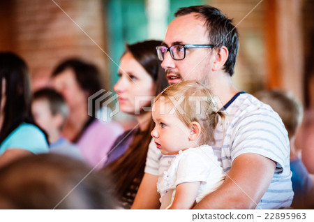 Family with daughter sitting in a crowd of people 22895963