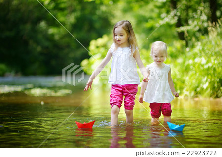 Two little sisters playing with paper boats 22923722